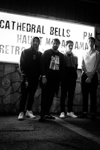 a group of men standing in front of a sign that says cathedral bells