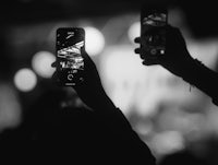 a black and white photo of people taking photos with their cell phones