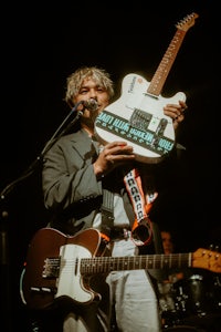 a man holding up a guitar in front of a microphone