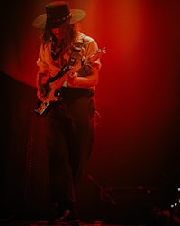 a man in a hat playing a guitar on stage