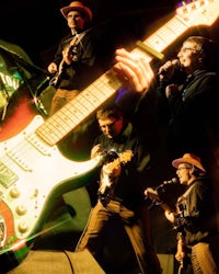 a group of people with guitars in front of a microphone