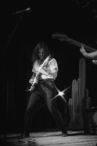a black and white photo of a man playing a guitar